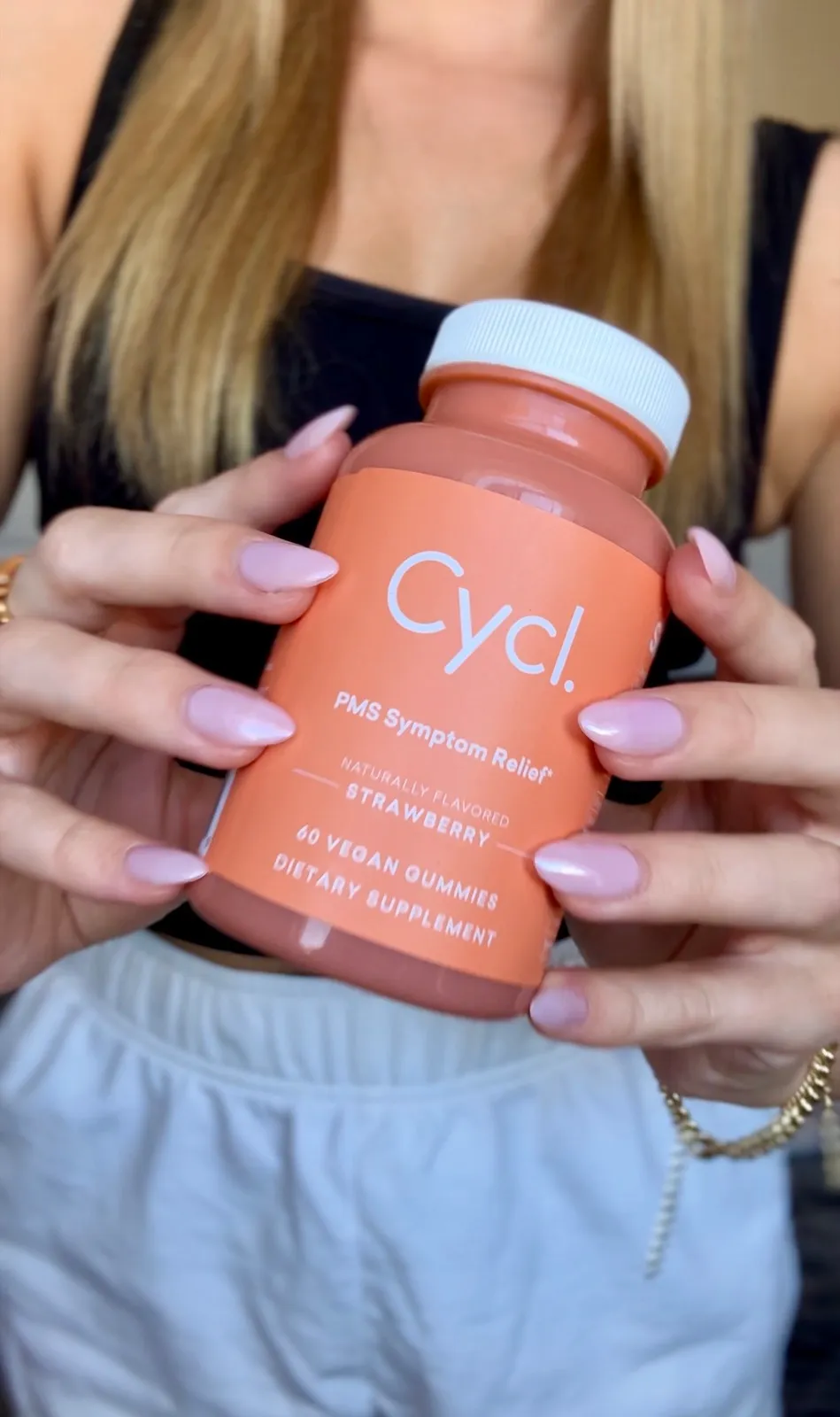 Hands holding a bottle of Cycl PMS Symptom Relief strawberry gummies