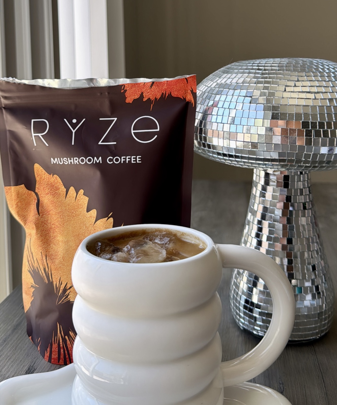 A RYZE mushroom coffee mug beside a disco ball