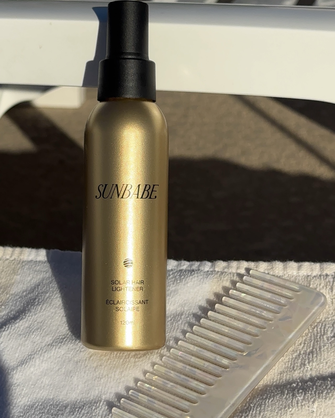 A gold Sunbae Hair spray bottle beside a comb